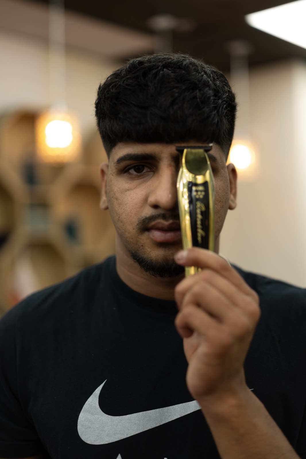 A barber holding clippers up at Ezz Cutz
