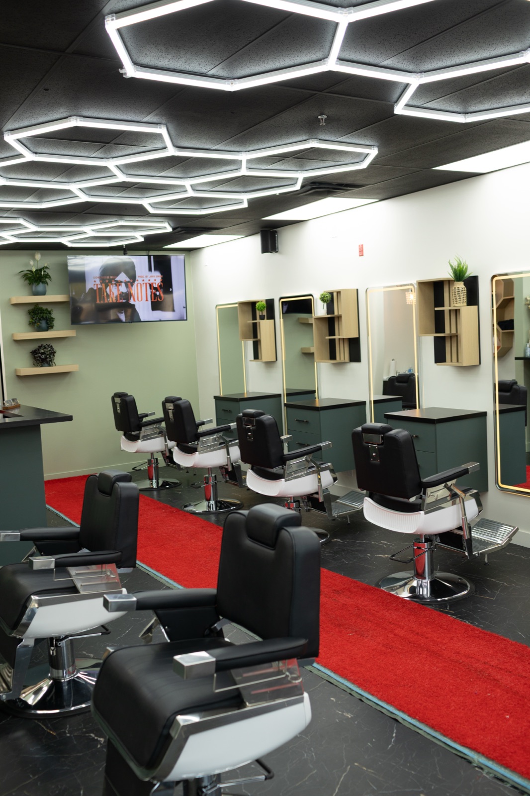 Row of barber chairs under honeycomb lighting at Ezz Cutz